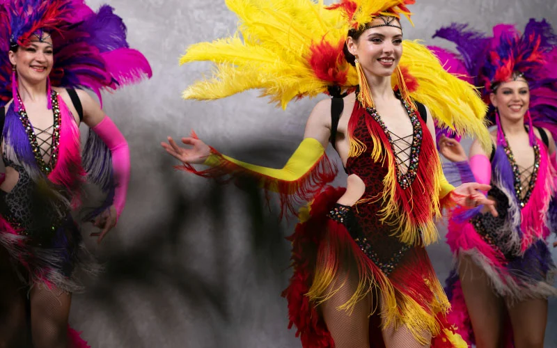 Carnival performers in elaborate feathered costumes dancing in the Notting Hill parade during summer bank holiday weekend