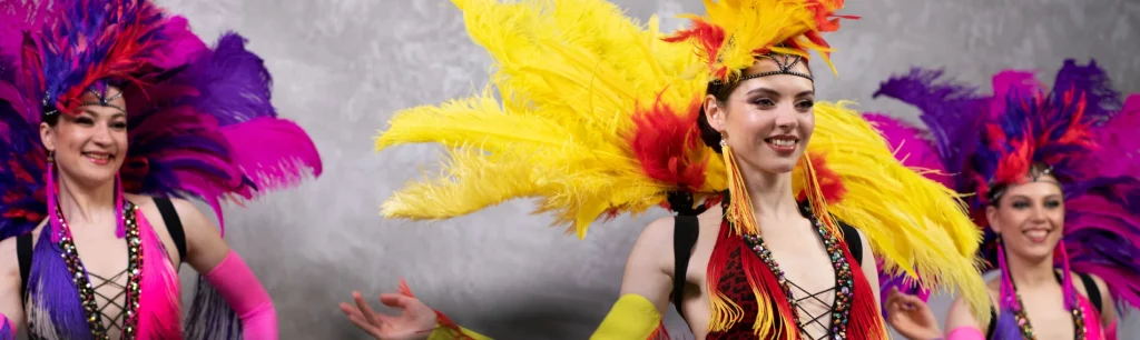 Carnival performers in elaborate feathered costumes dancing in the Notting Hill parade during summer bank holiday weekend, Notting Hill Carnival